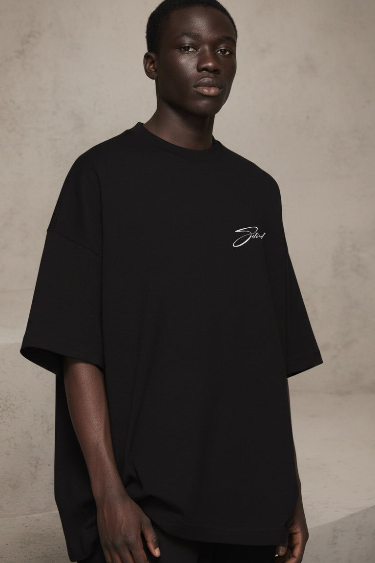 Person wearing a black t-shirt with a logo on a beige background