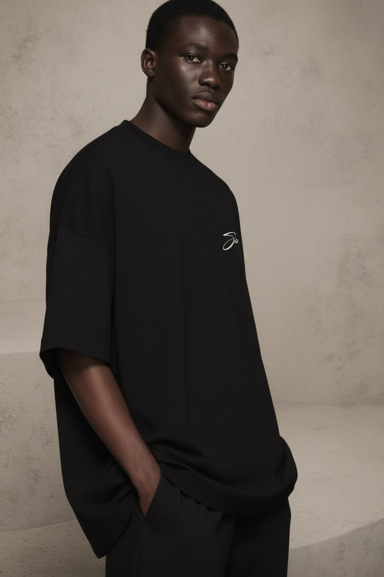 Person wearing a black t-shirt with a logo on a beige background