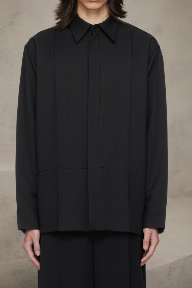 Person wearing a black shirt with a high collar against a neutral background