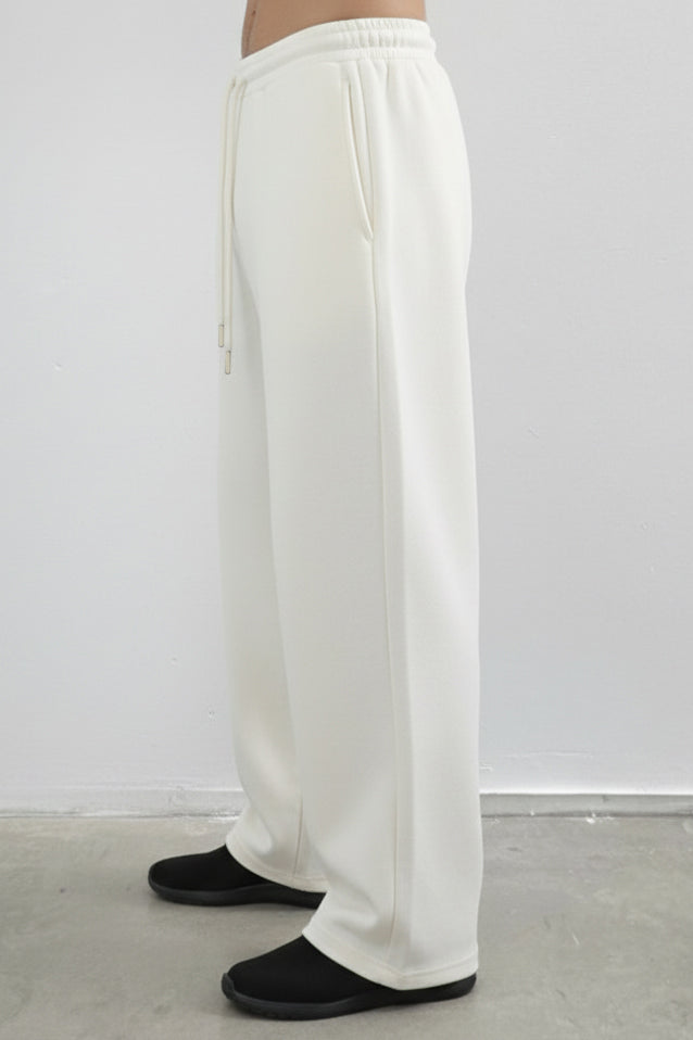 White pants worn by a person on a plain background